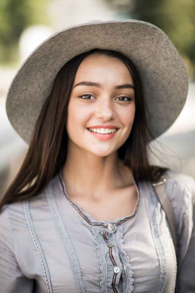 Outdoor portrait of a smiling young woman in a hat
